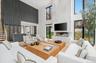 Living room with a large fireplace, a high ceiling, recessed lighting, and wood finished floors