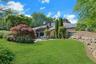 Colorful specimen trees, mature landscaping, and generous lawn space frame the pool area with beauty and privacy.