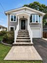 Exterior featuring gray siding, a covered entry porch, a bay window, and an attached garage with a white door.