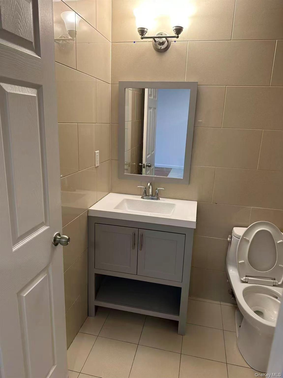 Half bath with tile walls, light tile patterned floors, and vanity