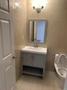 Half bath with tile walls, light tile patterned floors, and vanity