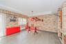 Dining room with brick wall, light wood-style floors, a tray ceiling, radiator heating unit, and recessed lighting