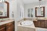 Primary bathroom with dual vanities, spa tub, toilet closet and walk-in shower