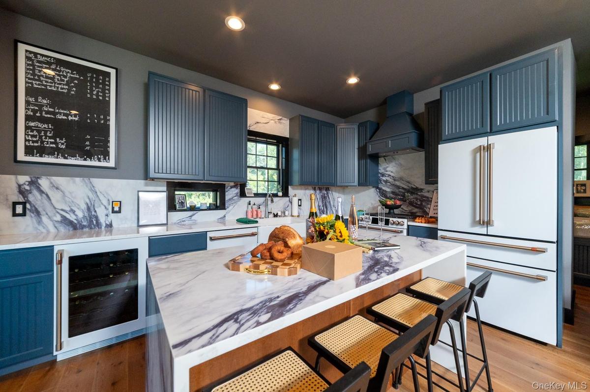 Kitchen with a breakfast bar area, white appliances, decorative backsplash, wine cooler, and a center island