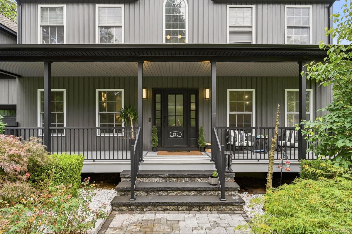 Inviting covered front porch with dark railing and columns