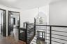 A dramatic second-floor overlook showcases the home’s cathedral-ceiling foyer and striking arched window, filling the space with natural light. Modern