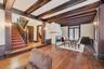 Living room featuring ornate columns, radiator, beam ceiling, a fireplace with flush hearth, and dark wood finished floors