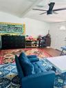 Living area featuring wood finished floors, ceiling fan, and beamed ceiling