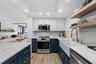 Cooking zone with LG induction range, marble backsplash, brass pull-down faucet, and open wood shelving.