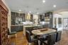 Kitchen with appliances with stainless steel finishes, a kitchen island with sink, wall chimney range hood, pendant lighting, and light hardwood / woo