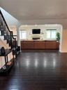 Unfurnished living room featuring stairway, arched walkways, dark wood-type flooring, and a tile fireplace