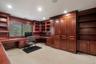 Built-in wood-finish cabinetry and shelving throughout, featuring a U-shaped desk with integrated drawers