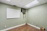 Neutral wall color with crisp white trim, wood-finish flooring, and drop ceiling with integrated fluorescent lighting