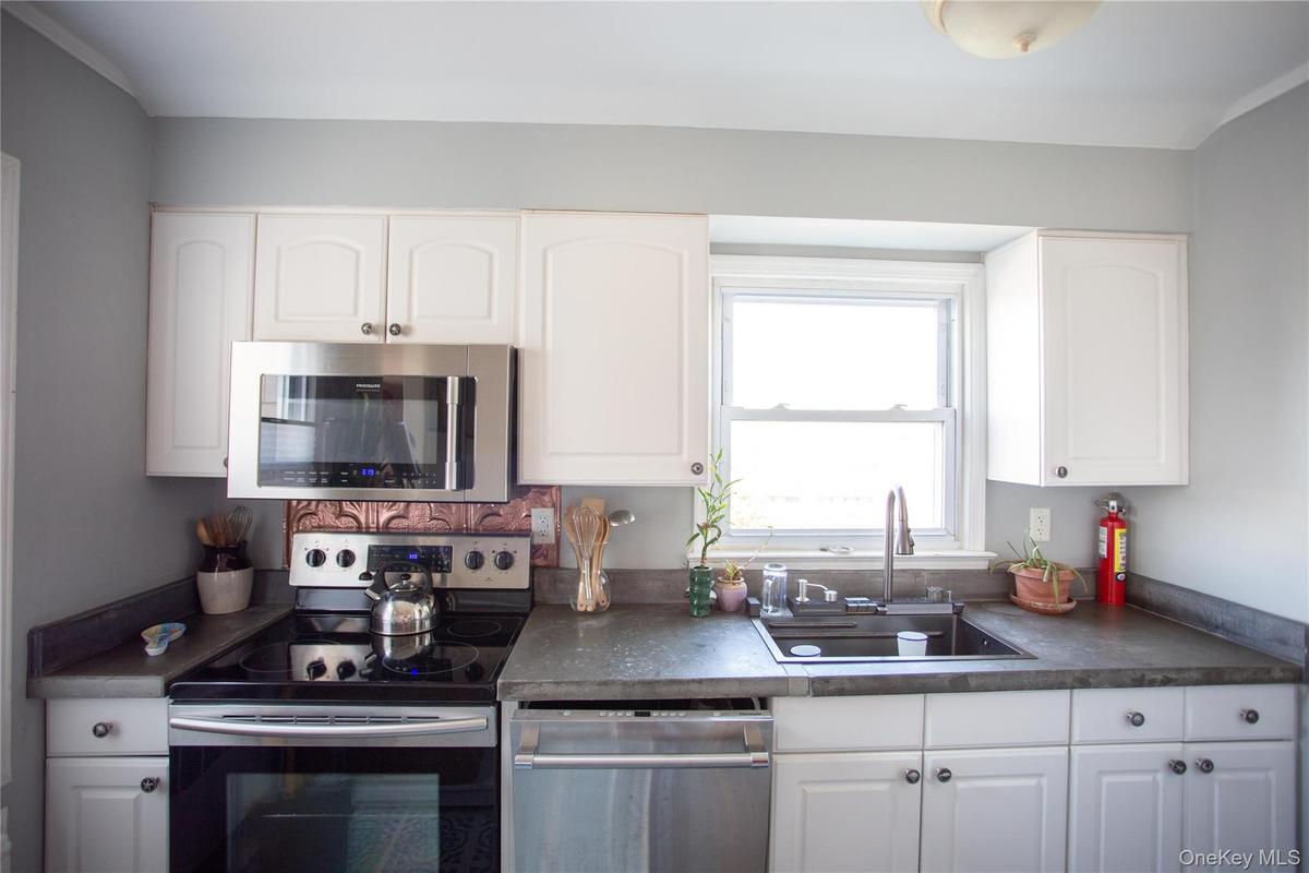 Kitchen featuring appliances with stainless steel finishes, dark countertops, and white cabinetry