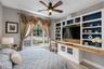 Room featuring a large window with draped valances, a ceiling fan with integrated lighting, and wood-finish flooring