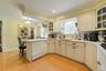 Kitchen featuring white dishwasher, a peninsula, a kitchen breakfast bar, glass insert cabinets, and backsplash