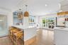 Kitchen with open shelves, a peninsula, light stone counters, ornamental molding, and a breakfast bar