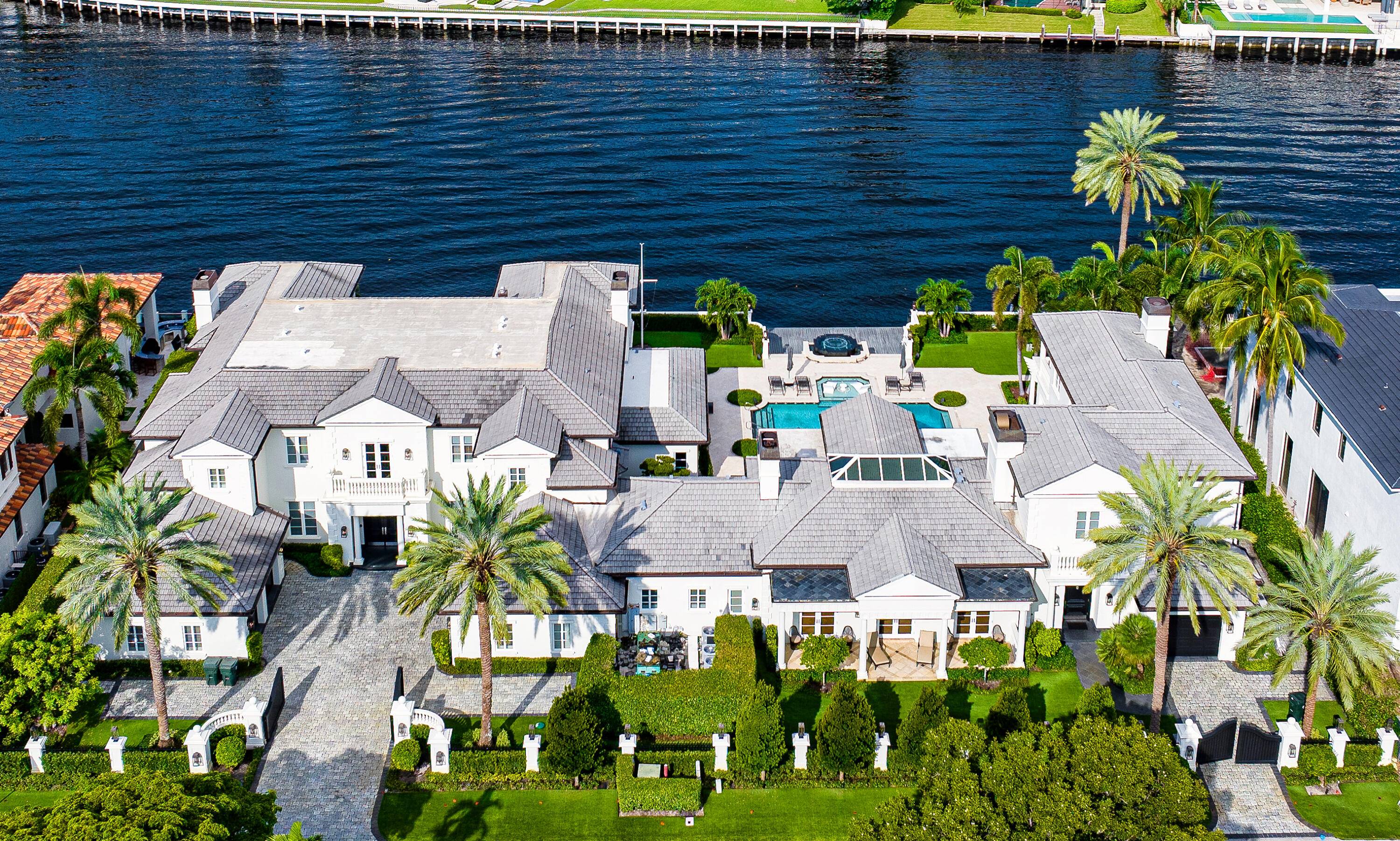 This Intracoastal Compound residing in The Estate Section, is approached on a gated cobblestone drive, surrounded by a pristine landscape complete with topiary and medjool date palms.