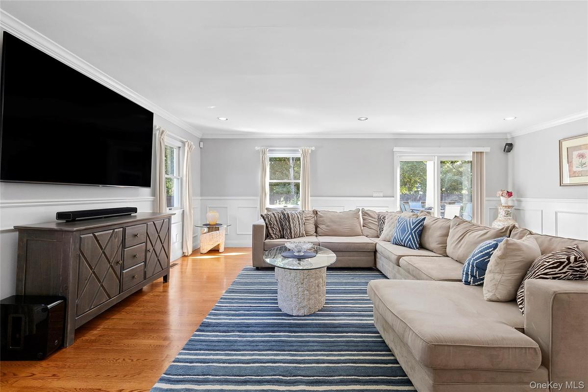 Living area featuring ornamental molding, light wood-style floors, recessed lighting, a decorative wall, and wainscoting