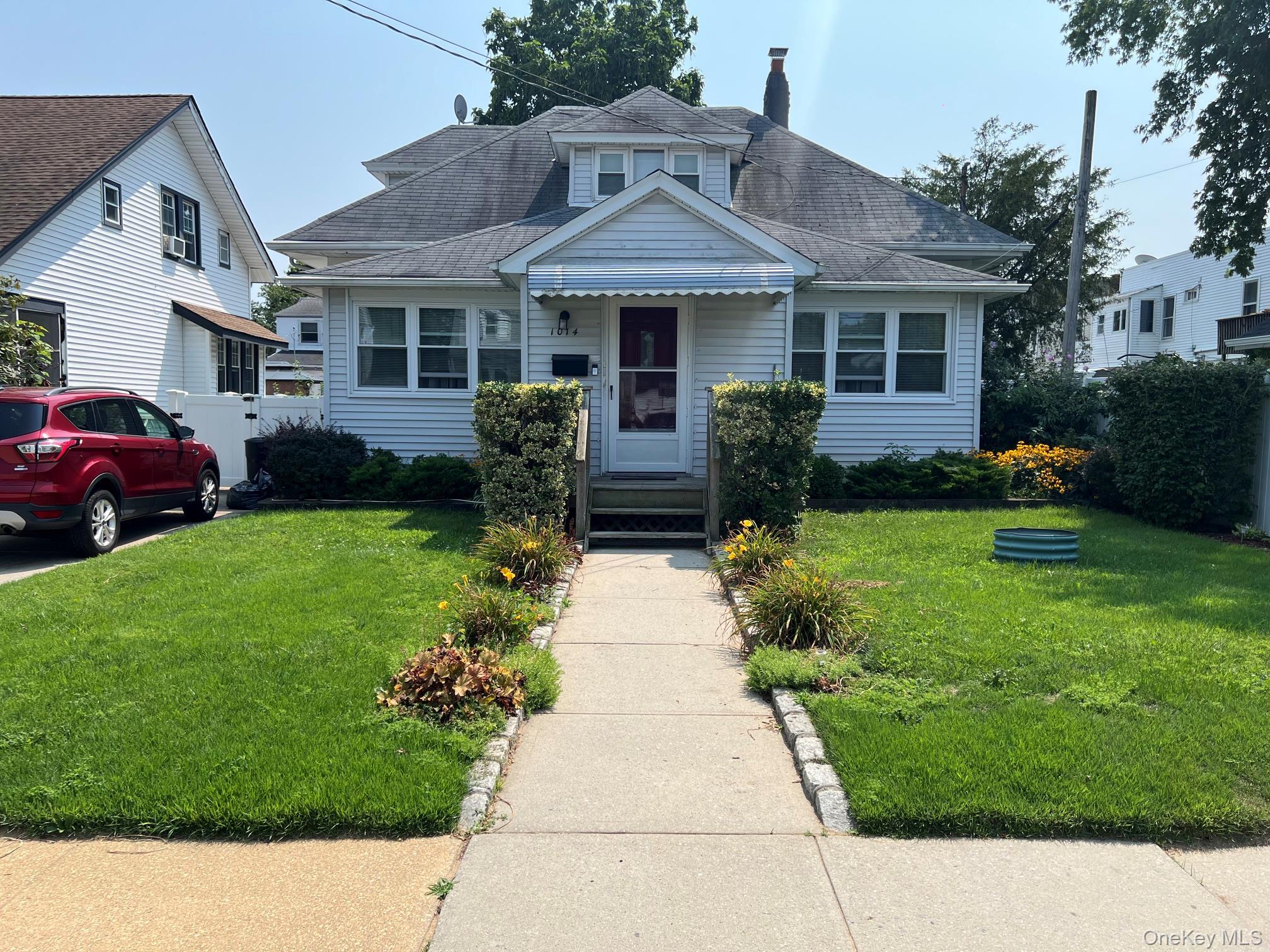 Front exterior featuring white siding, a prominent dormer, and a covered entry