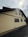 Exterior siding in a cream hue with brown trim and dark roofing