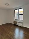 Spare room featuring a wall unit AC, radiator heating unit, baseboards, and dark wood-style flooring