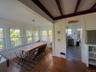 Dining room featuring dark wood-style floors, a decorative wall, and beamed ceiling