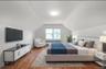 Bedroom featuring wood finished floors, radiator heating unit, and lofted ceiling