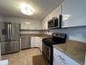 Bright white cabinetry and stainless appliances create a clean, coastal feel, effortless and welcoming