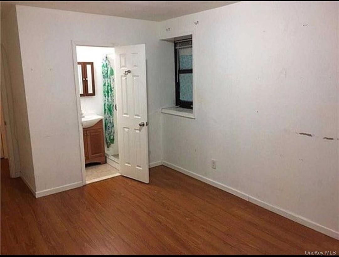 Unfurnished bedroom featuring dark wood-style floors and ensuite bath