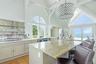 Kitchen featuring high vaulted ceiling, stainless steel fridge, a kitchen breakfast bar, plenty of natural light, and a water view