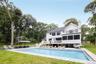 Rear view of house with a balcony, a patio, an outdoor pool, and a chimney