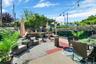 Expansive outdoor living area featuring a gravel patio, red brick pathway, lush perimeter greenery, and string lighting