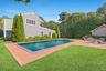 Outdoor pool with a patio area, a lawn, and view of wooded area