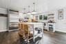 Kitchen with open shelves, hanging light fixtures, appliances with stainless steel finishes, and decorative backsplash