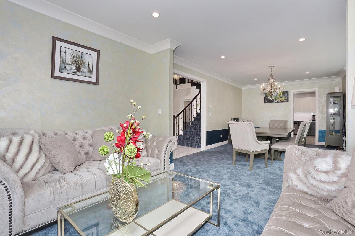 Living room with stairs, a chandelier, crown molding, recessed lighting, and carpet floors