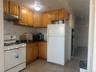Kitchen with white appliances, light tile patterned floors, brown cabinetry, and backsplash