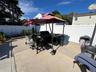 Paved patio area, white privacy fencing, and mature trees