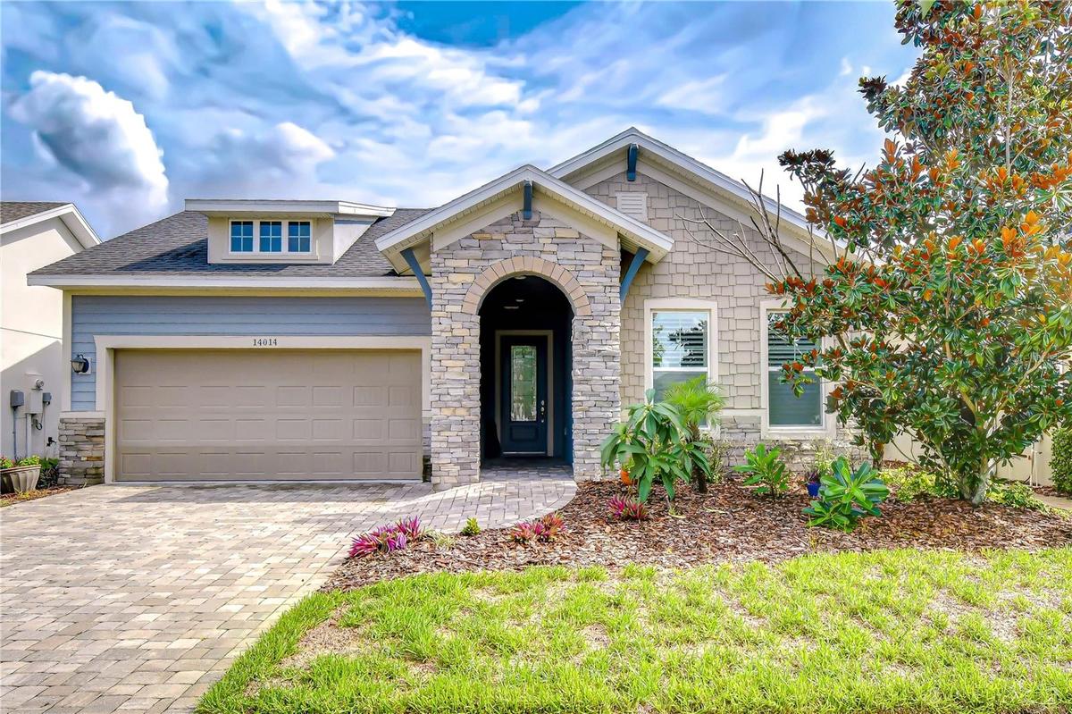 Beautiful David Weekley "Lorenzo" model with charming architectural details, paver driveway, manicured landscaping, and a rare three-car tandem garage