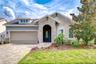 Beautiful David Weekley "Lorenzo" model with charming architectural details, paver driveway, manicured landscaping, and a rare three-car tandem garage
