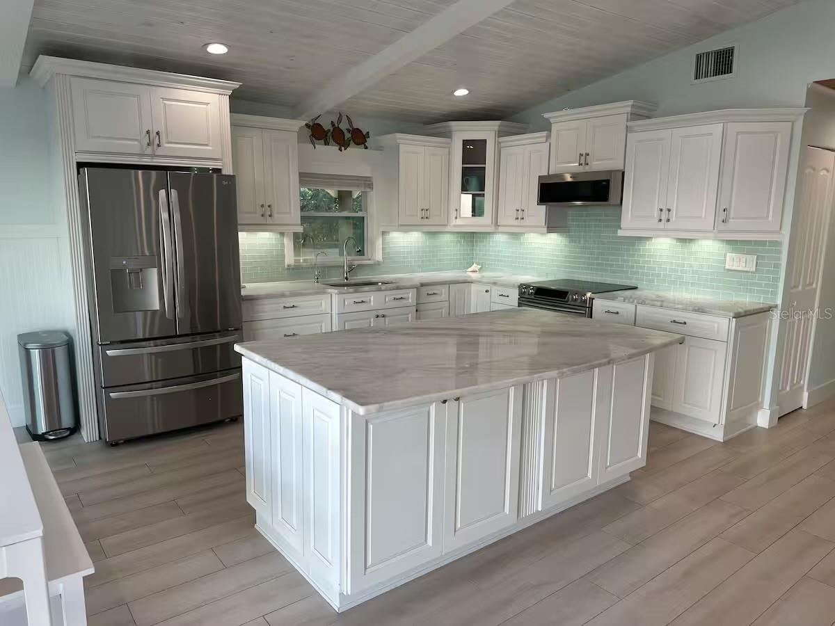 An enjoyable beachfront kitchen with sleek countertops and large windows offering a stunning ocean view.