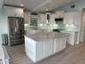 An enjoyable beachfront kitchen with sleek countertops and large windows offering a stunning ocean view.