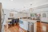 Kitchen featuring appliances with stainless steel finishes, light stone counters, light wood-type flooring, decorative light fixtures, and a center is