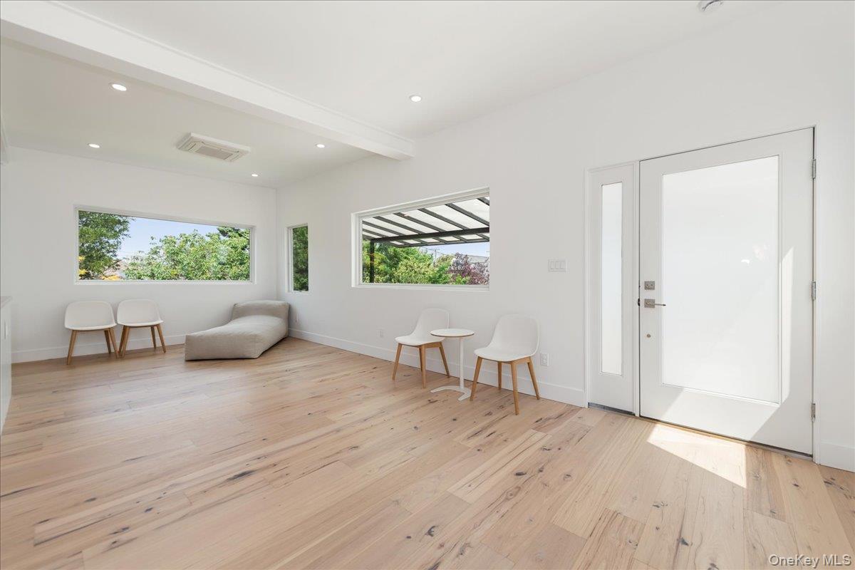 Sitting room with plenty of natural light, light wood finished floors, beamed ceiling, and recessed lighting