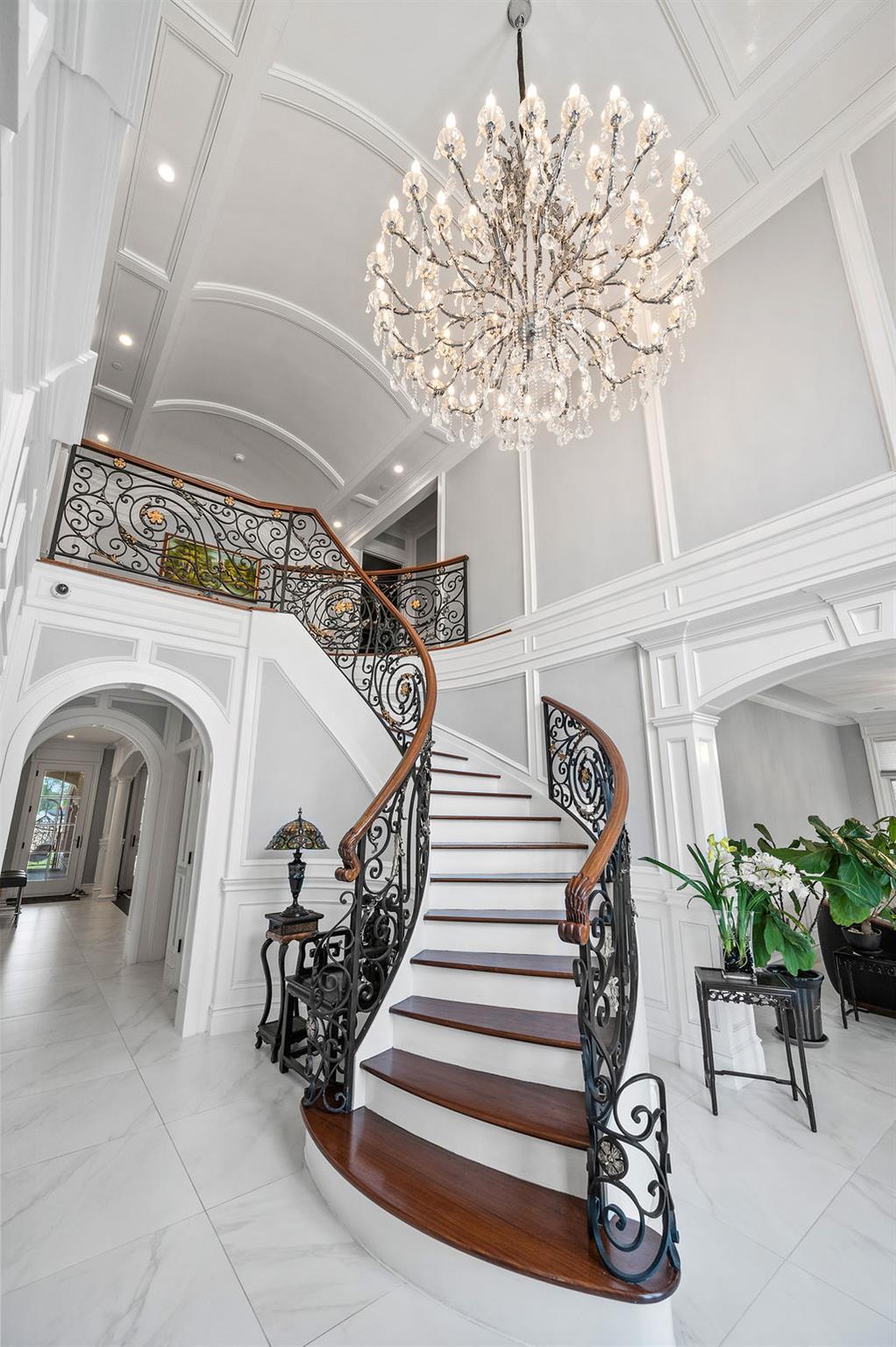 Staircase with arched walkways, a decorative wall, recessed lighting, a chandelier, and marble finish flooring