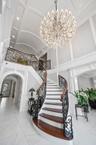Staircase with arched walkways, a decorative wall, recessed lighting, a chandelier, and marble finish flooring
