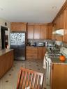 Kitchen featuring stainless steel range, paneled fridge, brown cabinets, decorative backsplash, and ventilation hood
