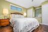 Master bedroom with Wood-finish flooring, two large windows with blinds, a window seat, and bi-fold closet doors