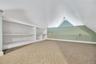 Vaulted ceiling with a recessed light fixture, built-in shelving, low-pile patterned carpeting, and painted accent walls