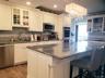 Kitchen featuring light wood-type flooring, decorative backsplash, a kitchen island, a sink, and appliances with stainless steel finishes